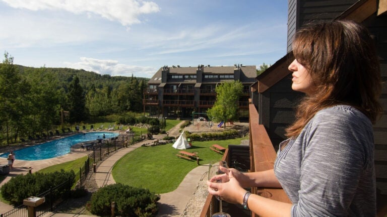 Woman on the deck of a condo overlooking the courtyard at Caribou Highlands